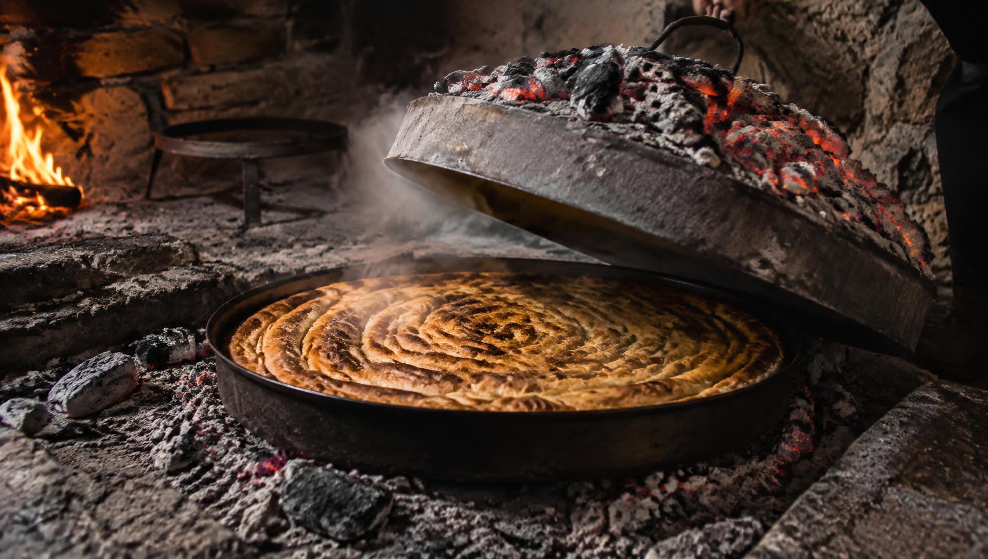 Podizanje sača sa tepsije pite nad žarom